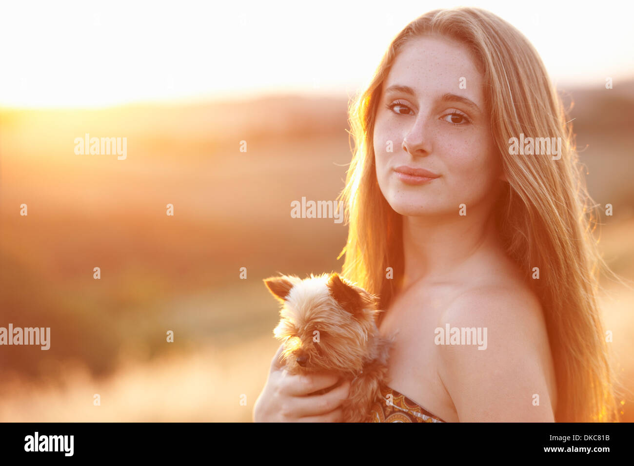 Adolescente in piedi in campo al crepuscolo holding cane domestico Foto Stock