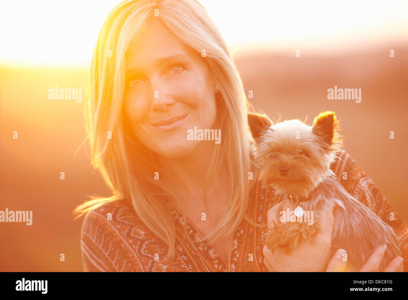 Donna in piedi nel campo al crepuscolo holding cane domestico Foto Stock