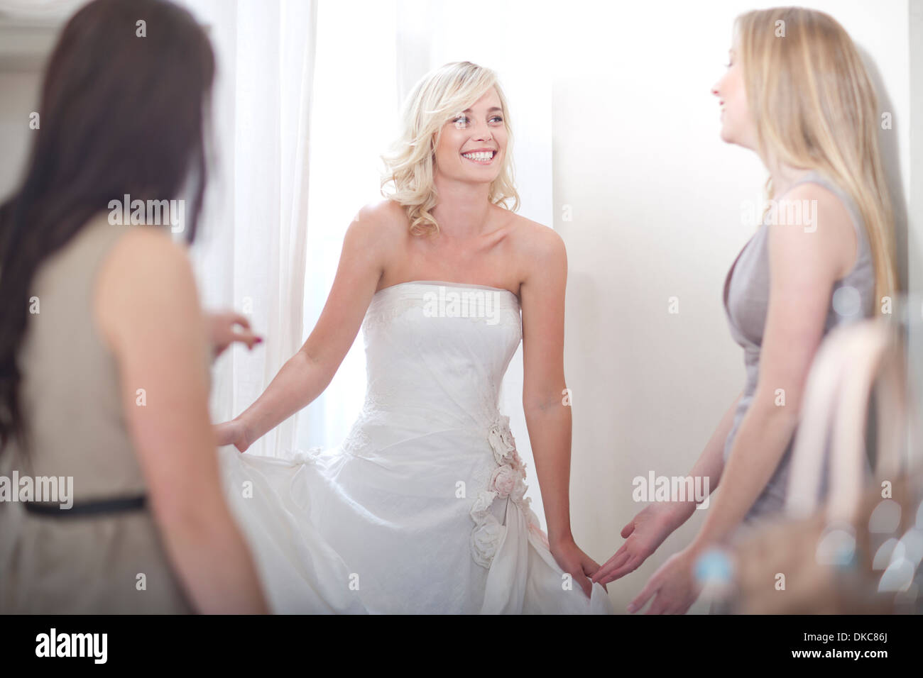 Giovane donna cercando in abito da sposa, con gli amici Foto Stock