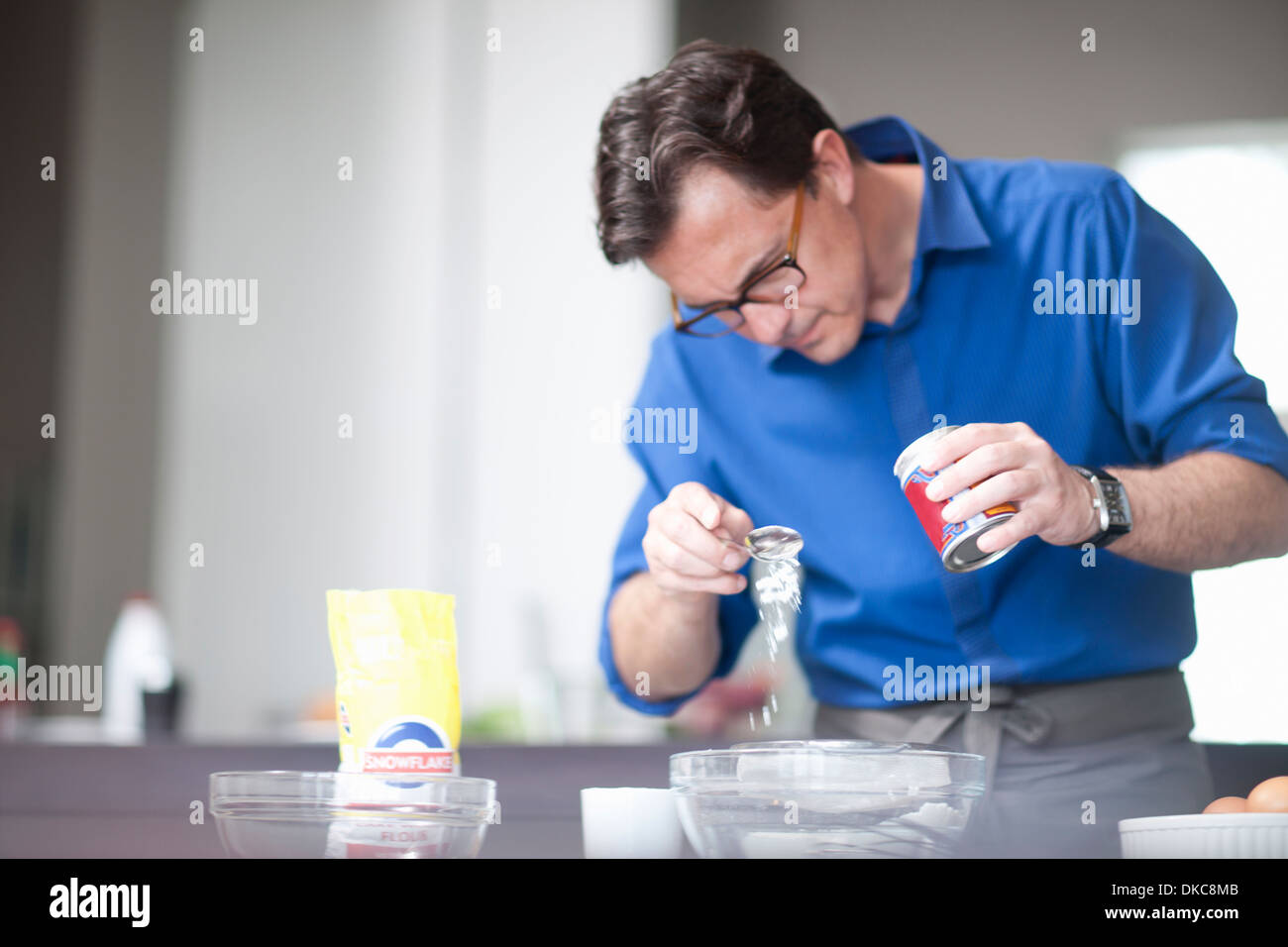 Uomo maturo di aggiungere 1 cucchiaio di lievito in polvere per tazza di miscelazione Foto Stock