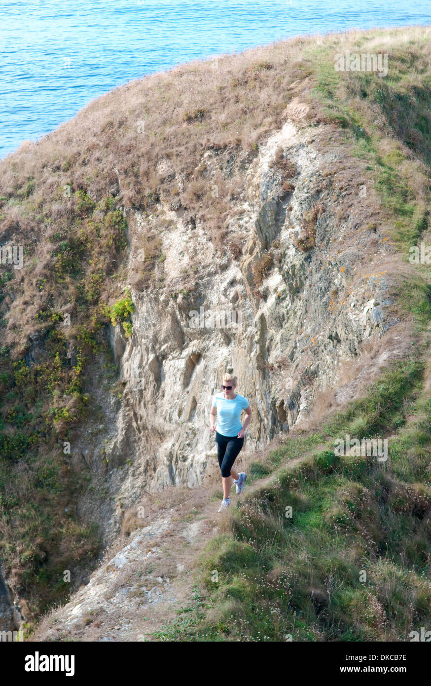 Metà donna adulta di jogging sul sentiero costiero, Thurlestone, Devon, Regno Unito Foto Stock