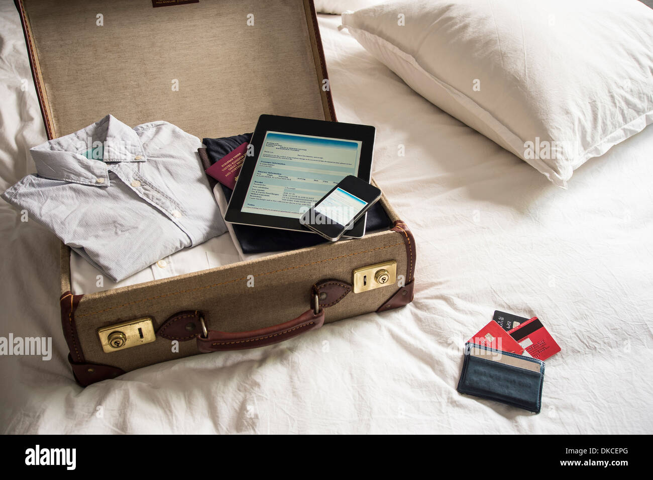 Aprire la valigia sul letto con tavoletta digitale e il telefono cellulare Foto Stock
