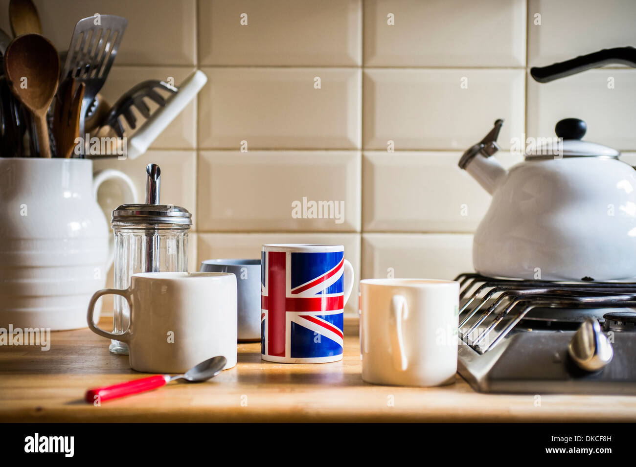 Banco di cucina con brocca di utensili e tazze da caffè Foto Stock