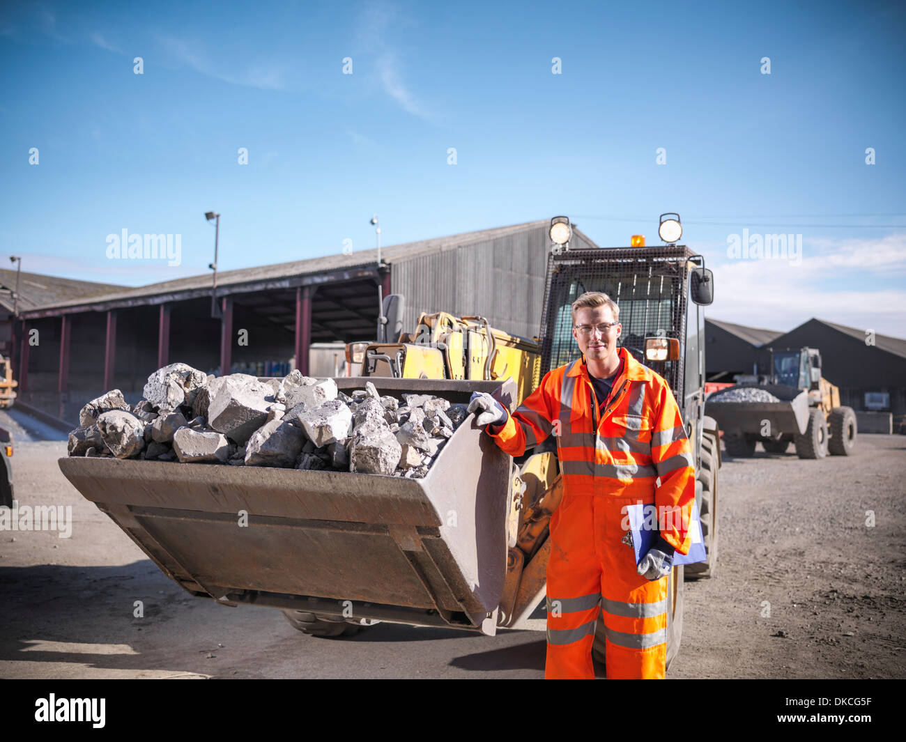 Ritratto di lavoratore in indumenti da lavoro riflettente con dumper di frantumato di titanio Foto Stock