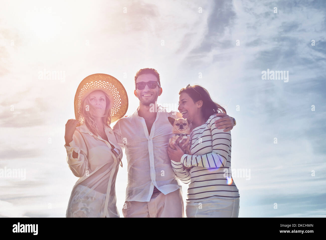 Giovane uomo con le braccia intorno a due giovani donne Foto Stock