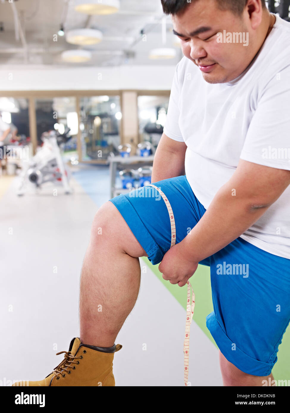 Il sovrappeso uomo misura le dimensioni della gamba Foto Stock