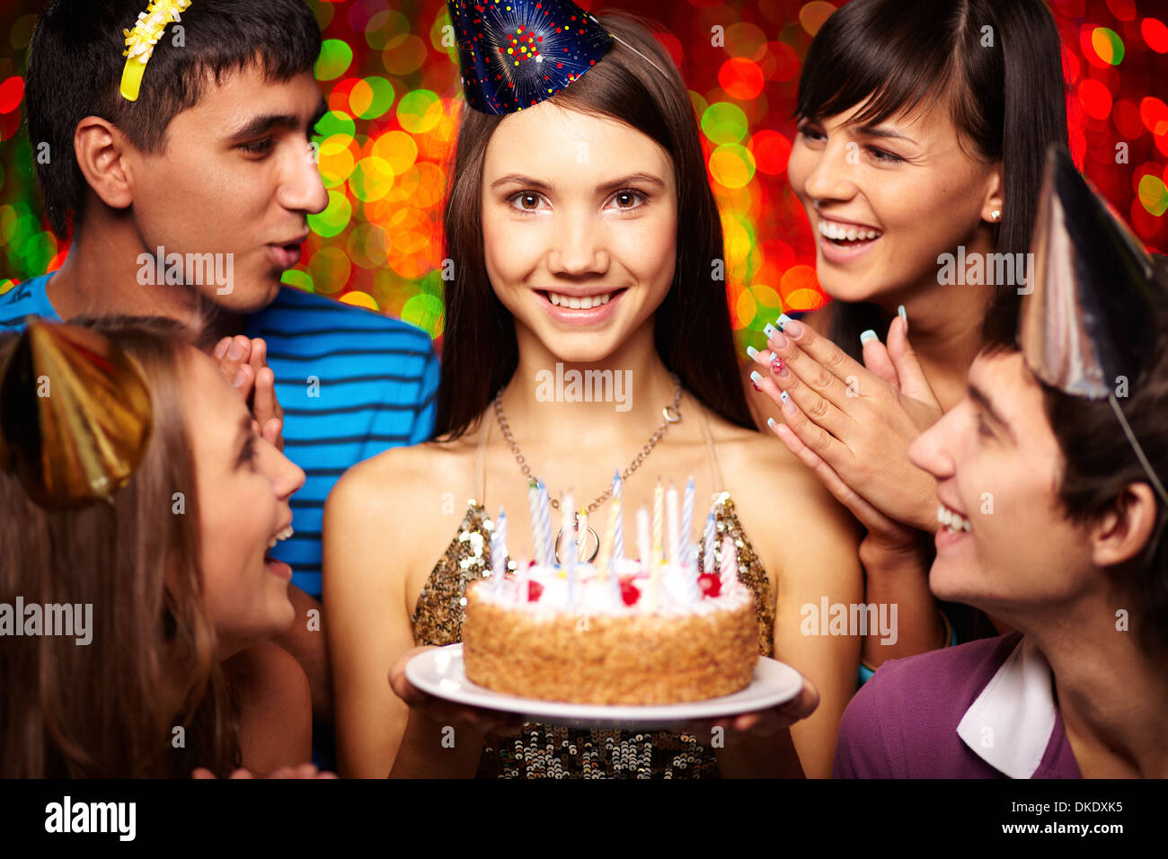 Ritratto di gioiosa ragazza con torta di compleanno circondato da amici di partito Foto Stock