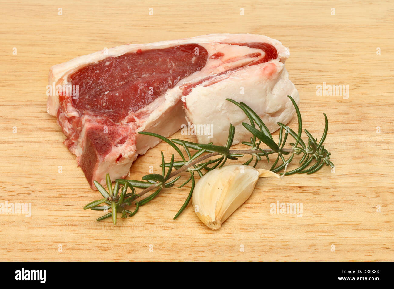 Materie lamb chop, rosmarino e aglio su una tavola di legno Foto Stock