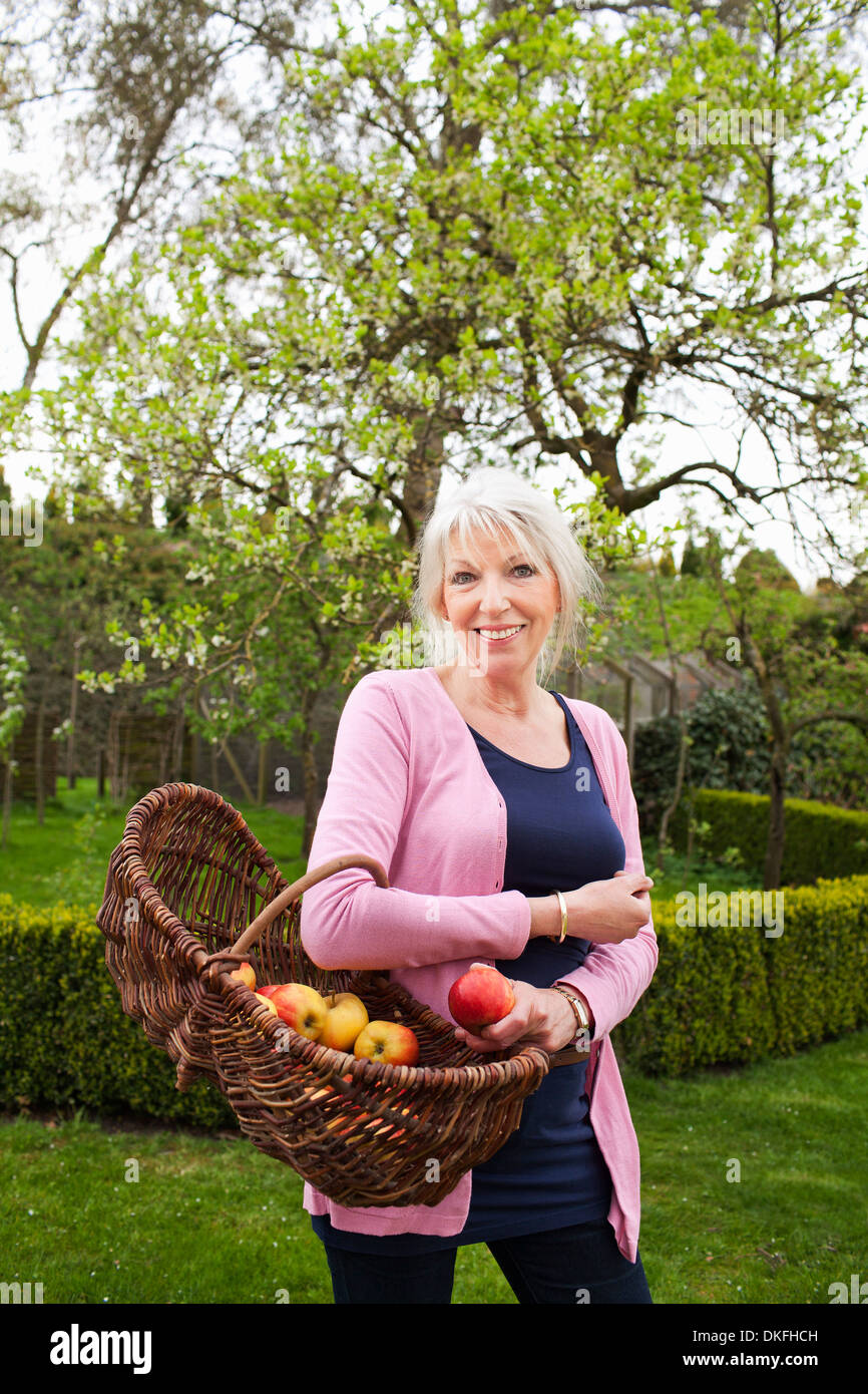Ritratto di donna matura con cesto di mele Foto Stock