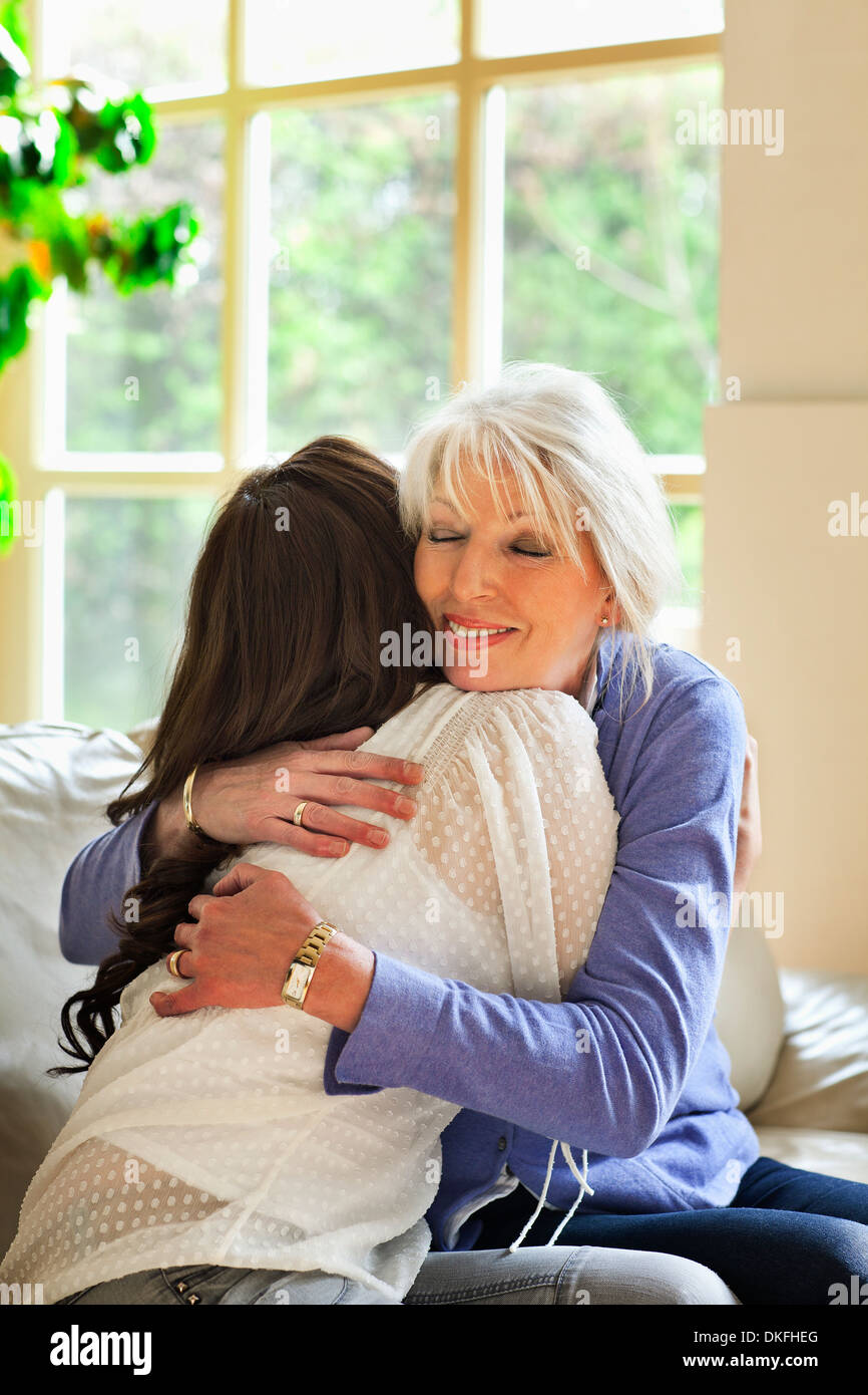 Madre e figlia abbracciando sul divano Foto Stock