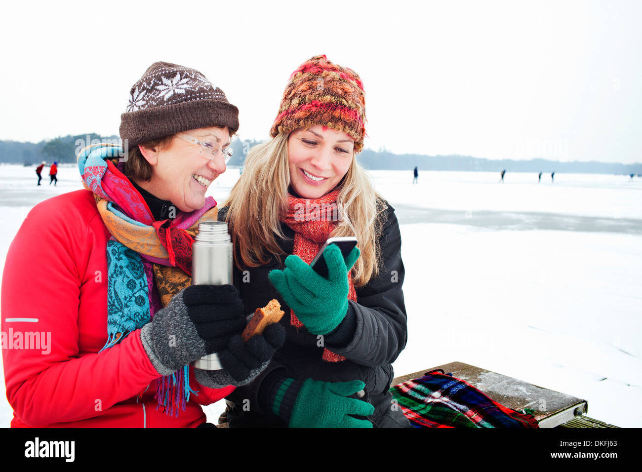 Le donne aventi potabile calda e guardando a smartphone Foto Stock