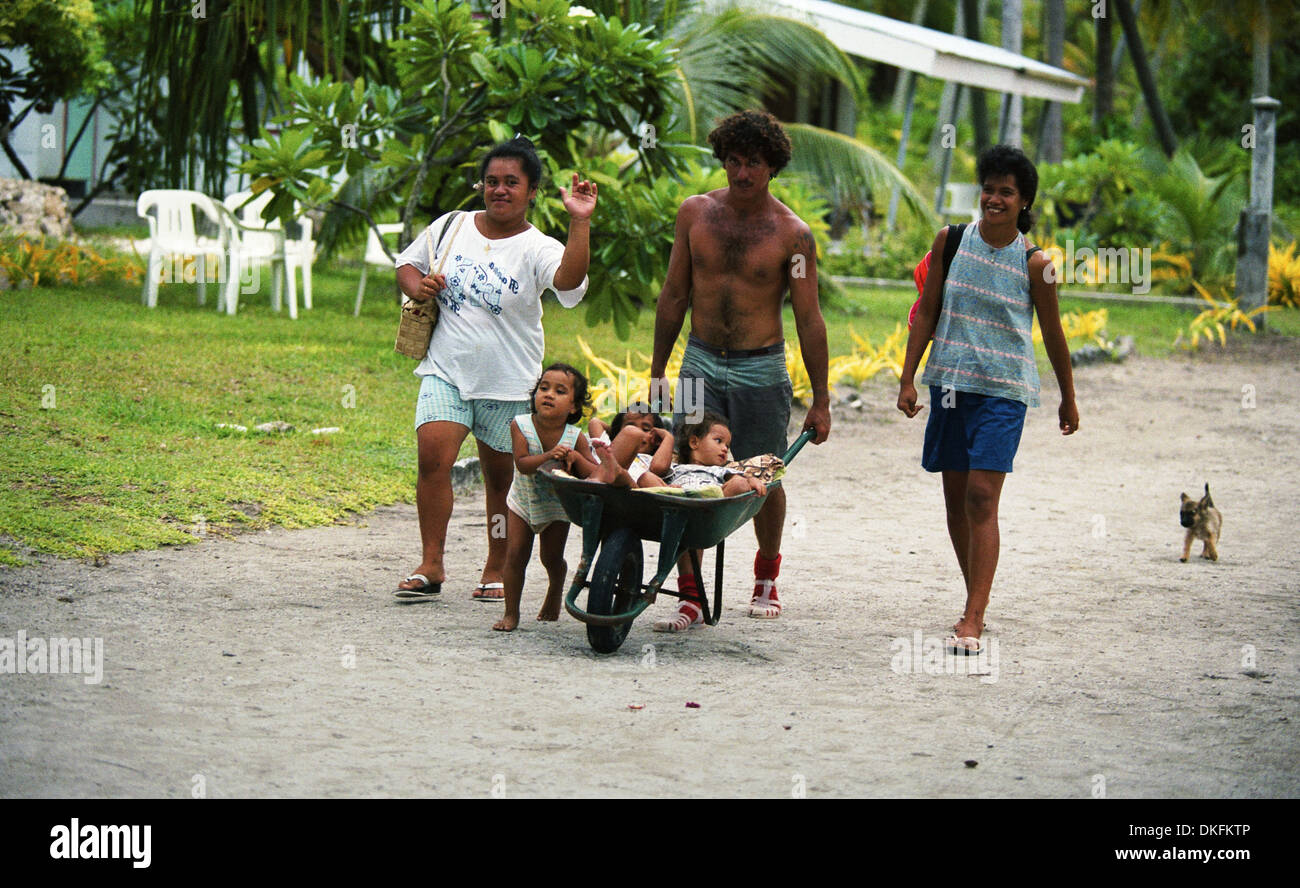 Un padre di trasportare i suoi figli in una carriola in l'isola di Raroia, Polinesia Francese Foto Stock