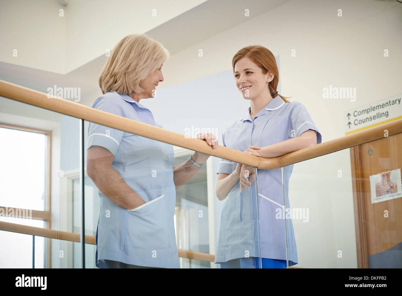 Due infermieri femmina chattare su atrio ospedale balcone Foto Stock