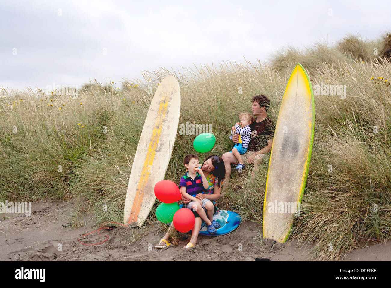 Famiglia con due ragazzi sulla spiaggia con tavole da surf Foto Stock