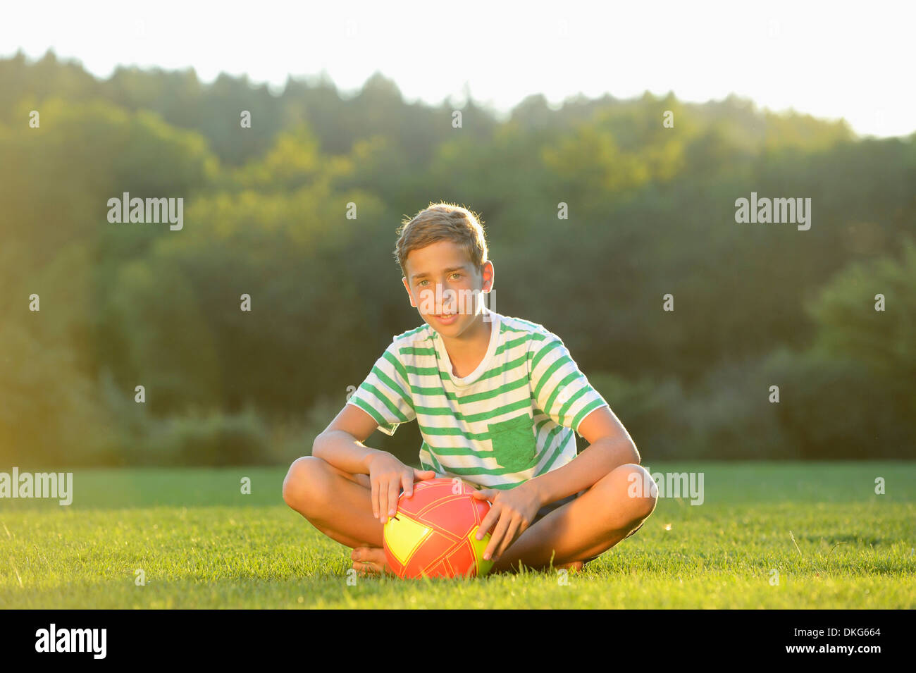 Teeange ragazzo seduto con calcio sul prato, Alto Palatinato, Baviera, Germania, Europa Foto Stock