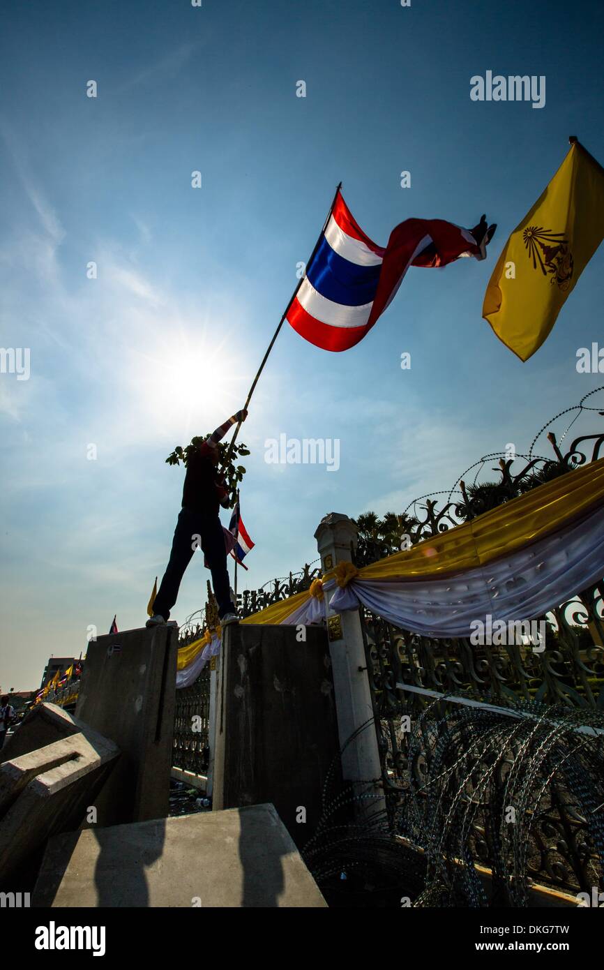 Bangkok, Tailandia. 3 dicembre, 2013. Un governo anti-protester permanente sulla sommità di barriere in calcestruzzo e sventolare la bandiera nazionale Tailandese di fronte la sede del governo di Bangkok. Thailandia. La polizia rimossi gli ostacoli che impediscono di accedere al complesso del governo dopo una settimana di violenti scontri, consentendo manifestanti hanno libero accesso al Governo complessa.Foto: Gavin Gough/NurPhoto Credito: Gavin Gough/NurPhoto/ZUMAPRESS.com/Alamy Live News Foto Stock