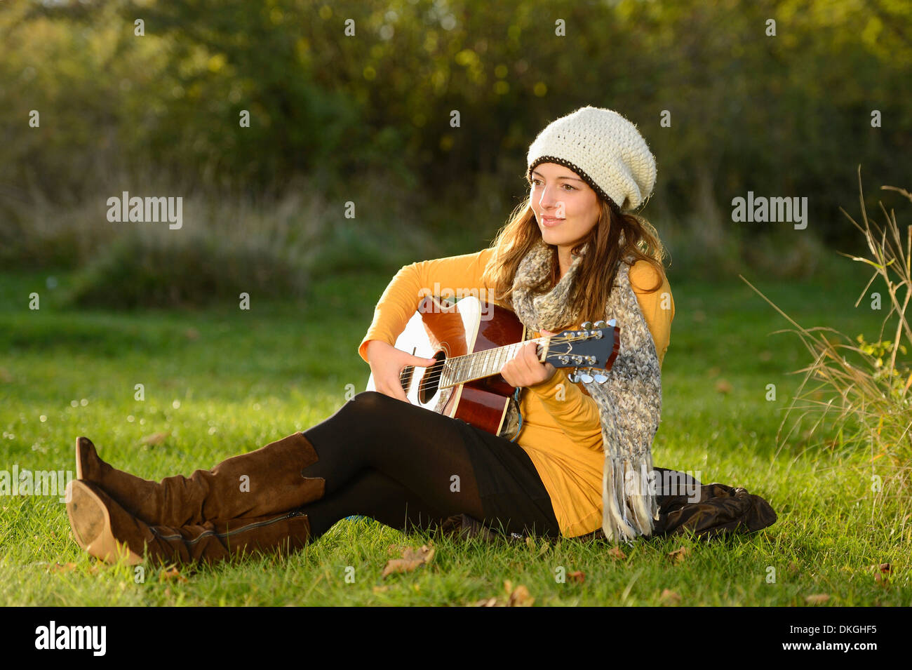 Sorridente giovane donna a suonare la chitarra in autunno Foto Stock