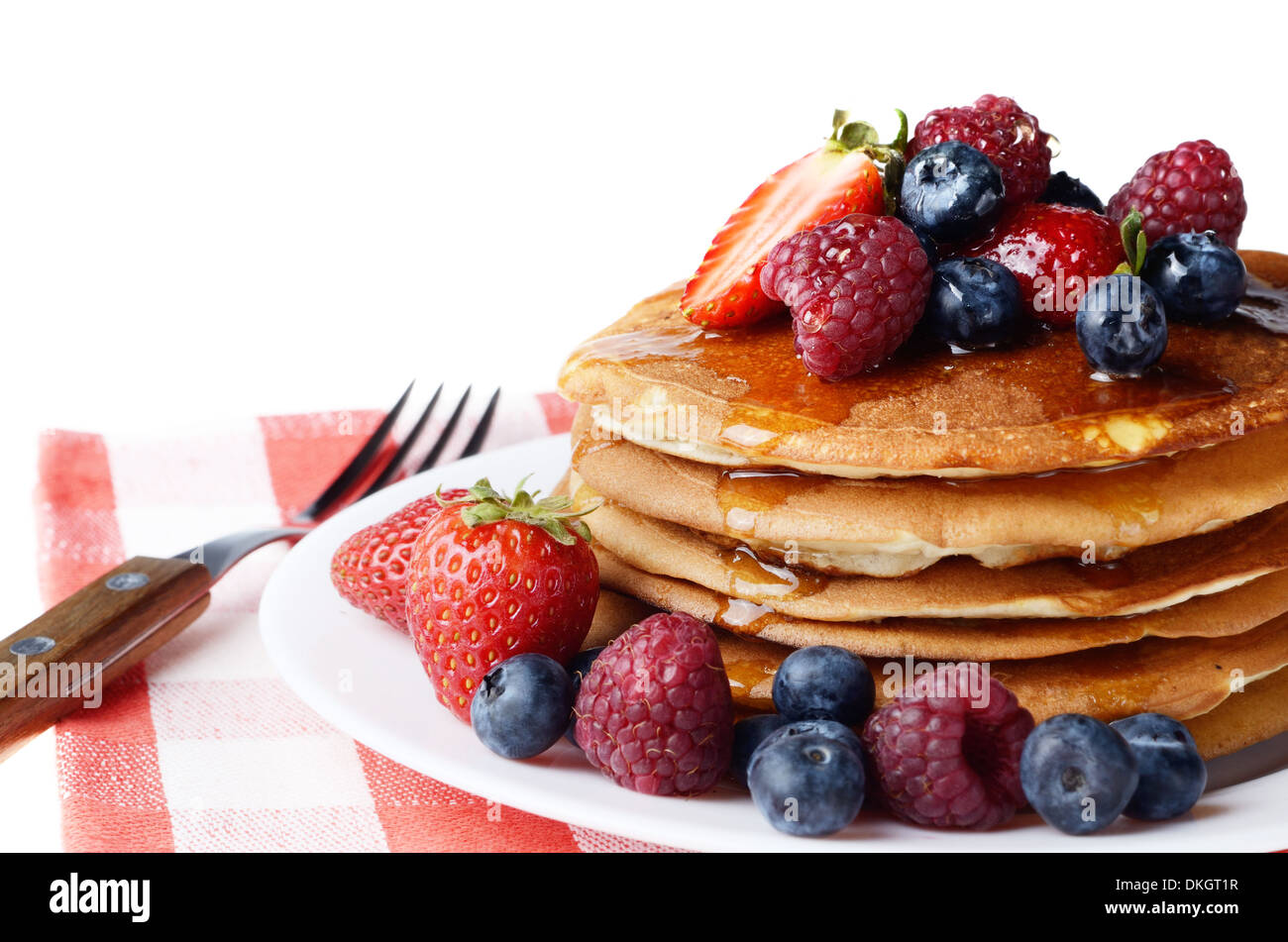 Piastra di colore bianco pieno di pancake con Fragole Lamponi Mirtilli e miele isolato su bianco Foto Stock