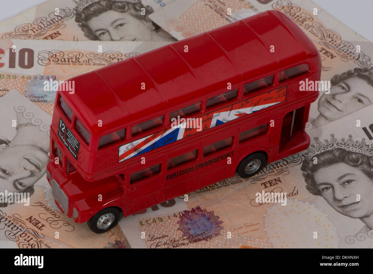 Un bus rosso su una pila di dieci Pound note Foto Stock