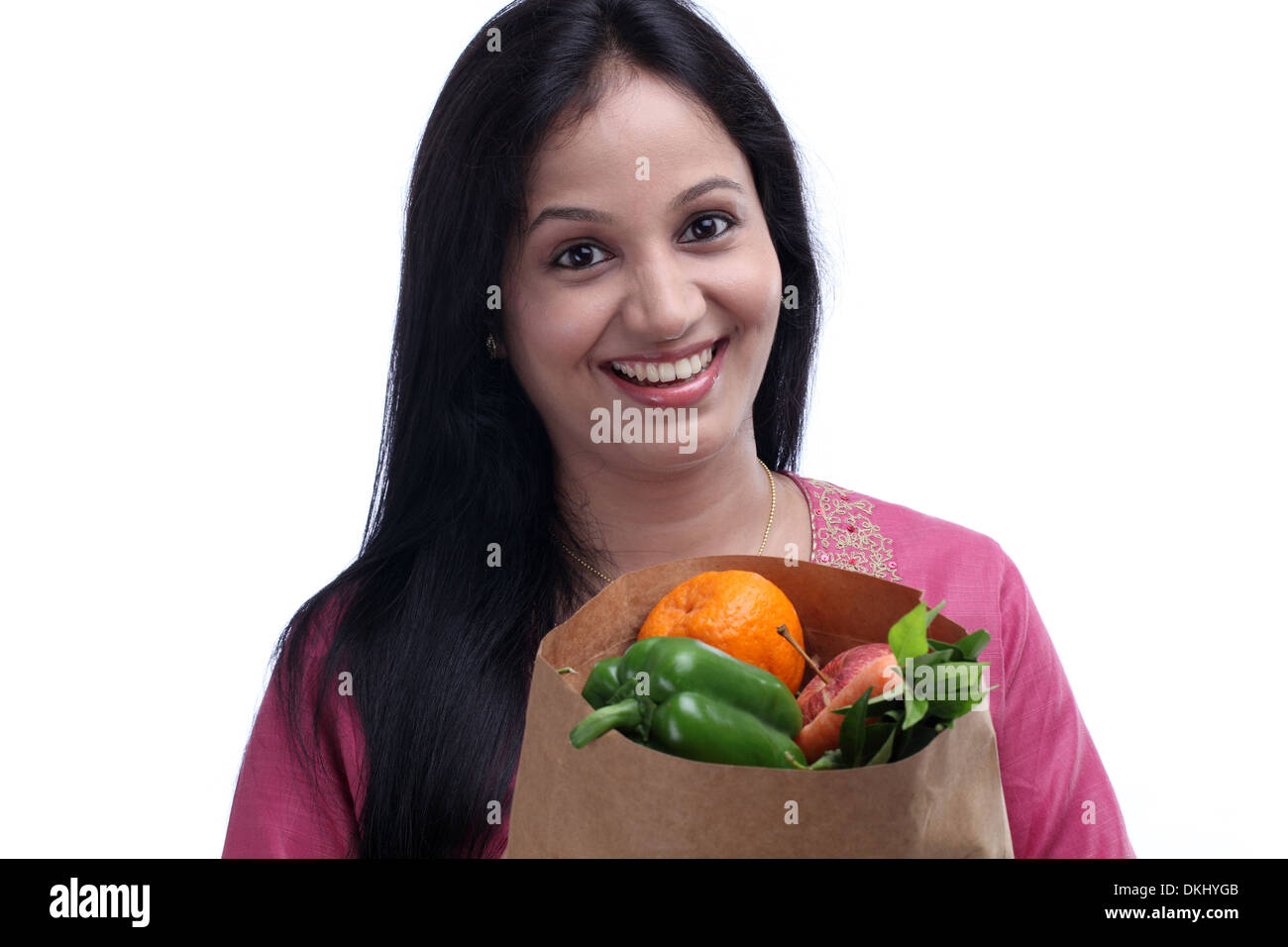 Allegro giovane donna con un sacco di negozi di generi alimentari pieno di frutta e verdura Foto Stock