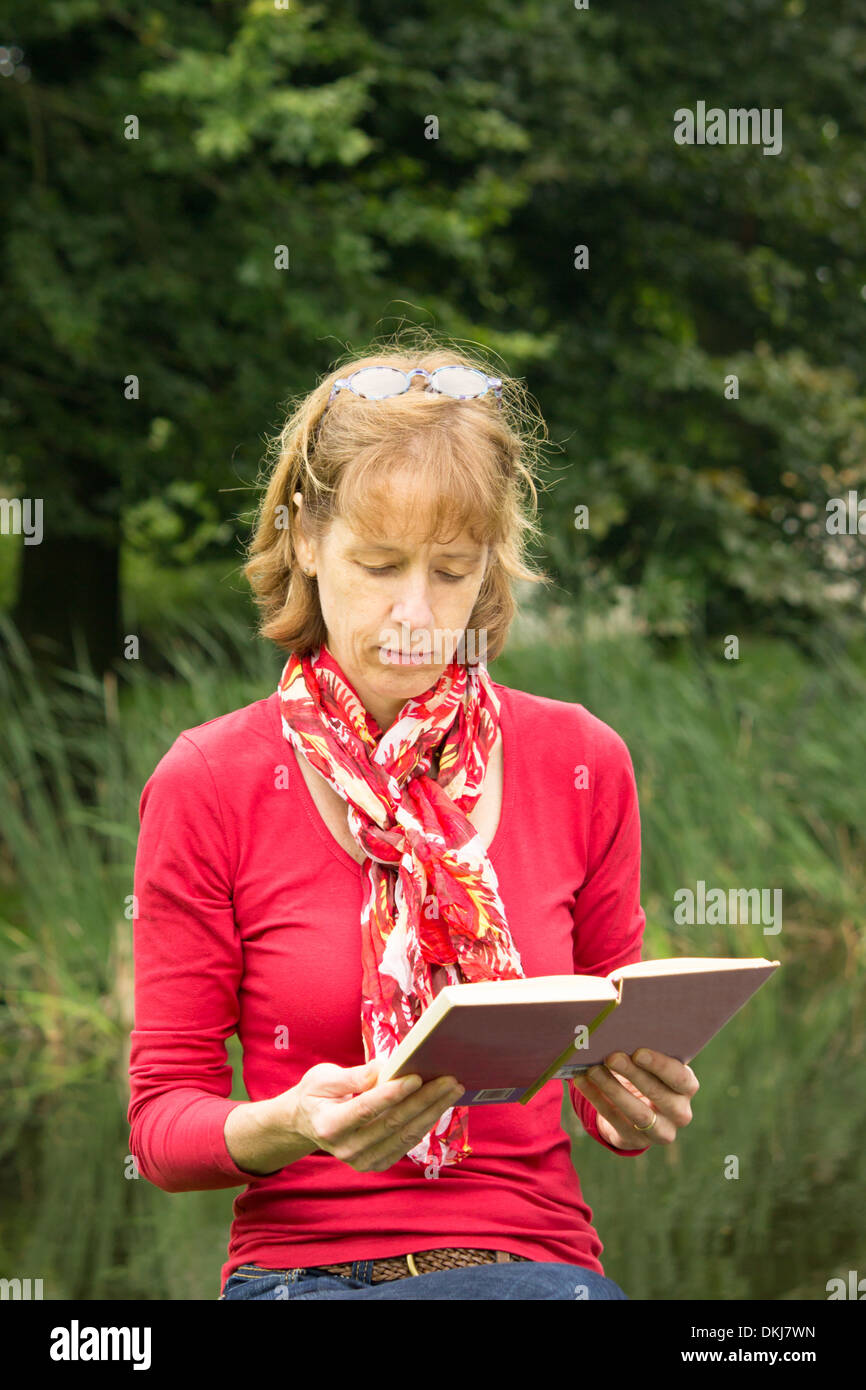 Donna di mezza età la lettura di un libro a carattere gratuito Foto Stock