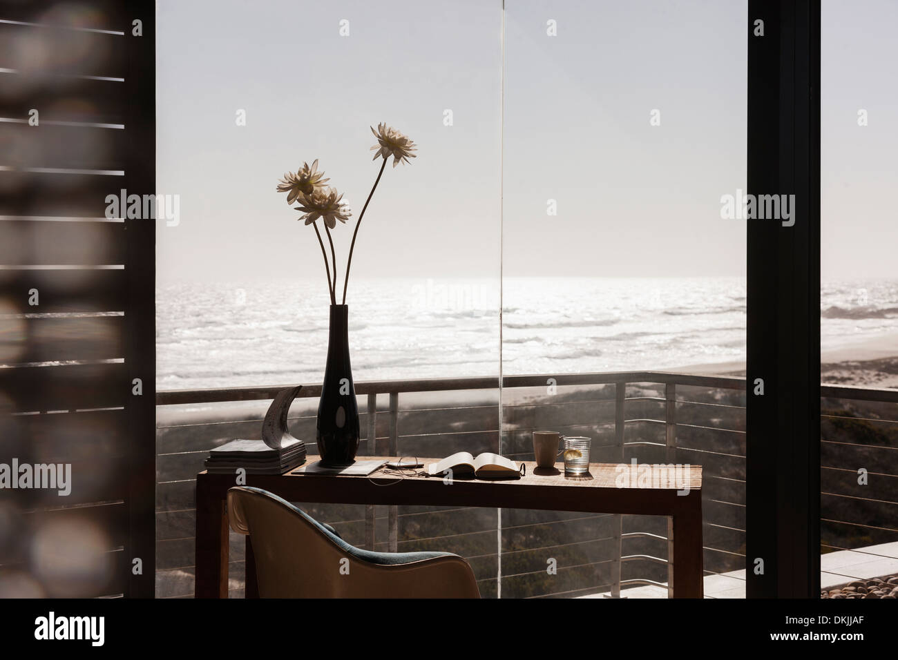 Vaso di fiori sulla scrivania in modern home office con vista sull'oceano Foto Stock