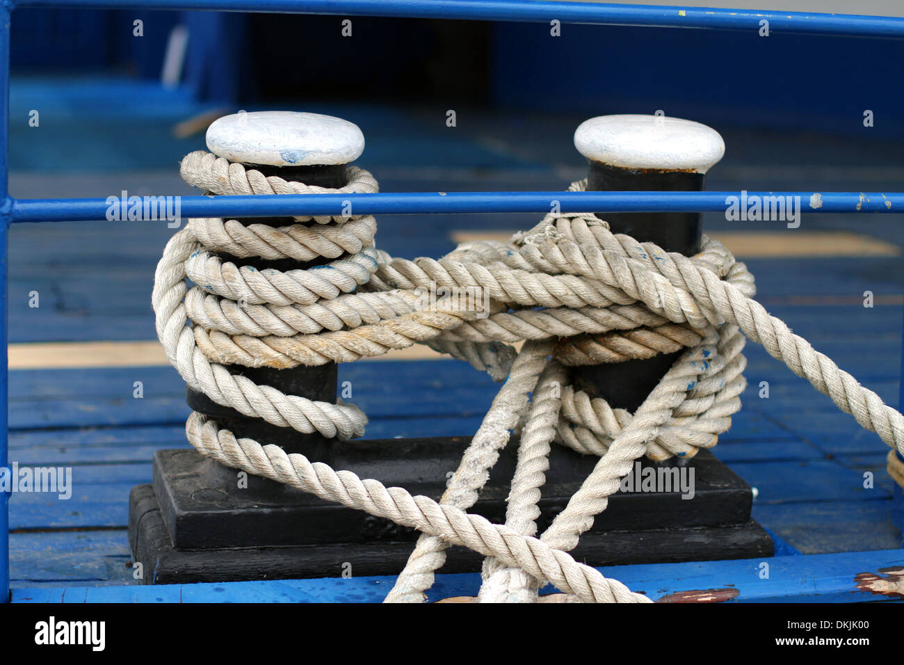 Close-up di una cima di ormeggio con una estremità annodata legato attorno un gancio su un molo in legno/ Nautico corda di ormeggio Foto Stock