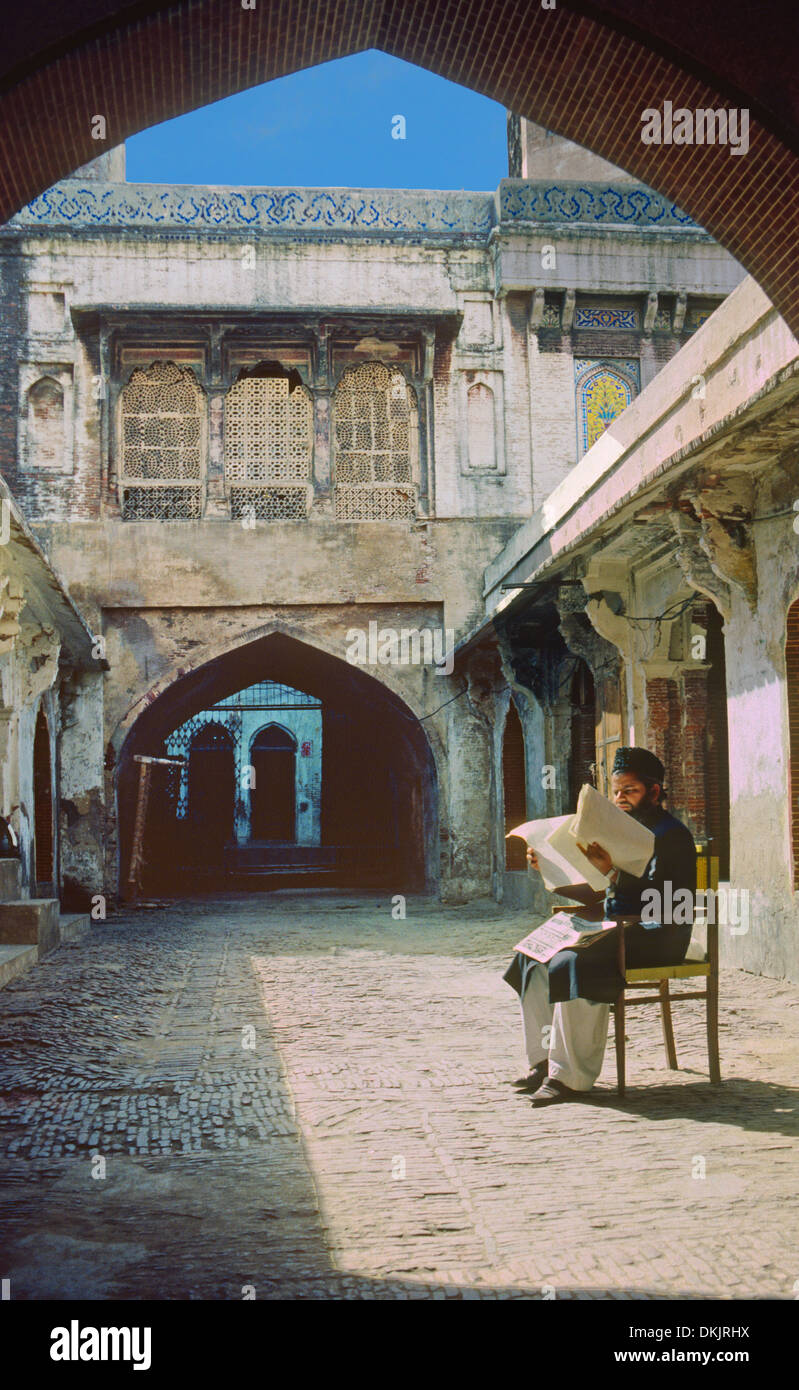 Seduto mullah lettura Corano nel cortile vecchia moschea a Lahore in Pakistan Foto Stock