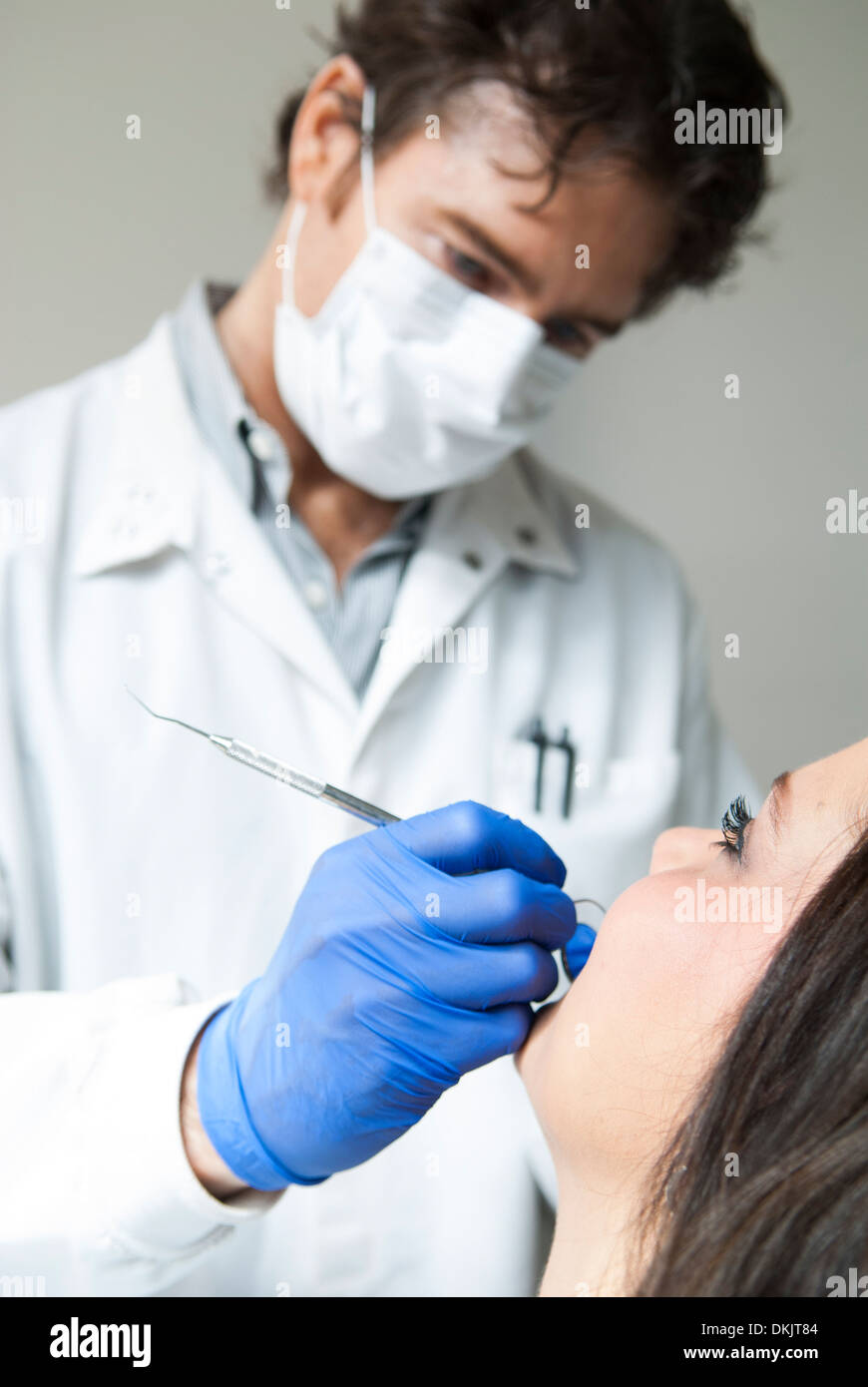 Dentista maschio indossando guanti blu esaminando sorridente femmina paziente dentale Foto Stock