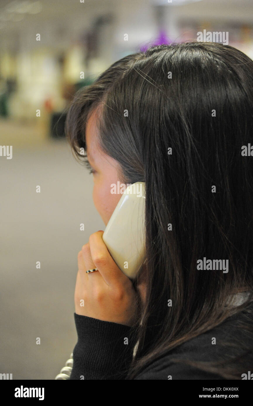 Giovane donna a parlare su un telefono di rete fissa in un ambiente di ufficio Foto Stock