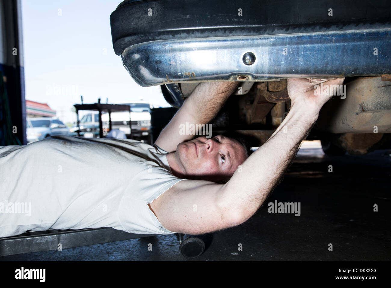 Meccanico maschio lavora al di sotto di un automobile Foto Stock