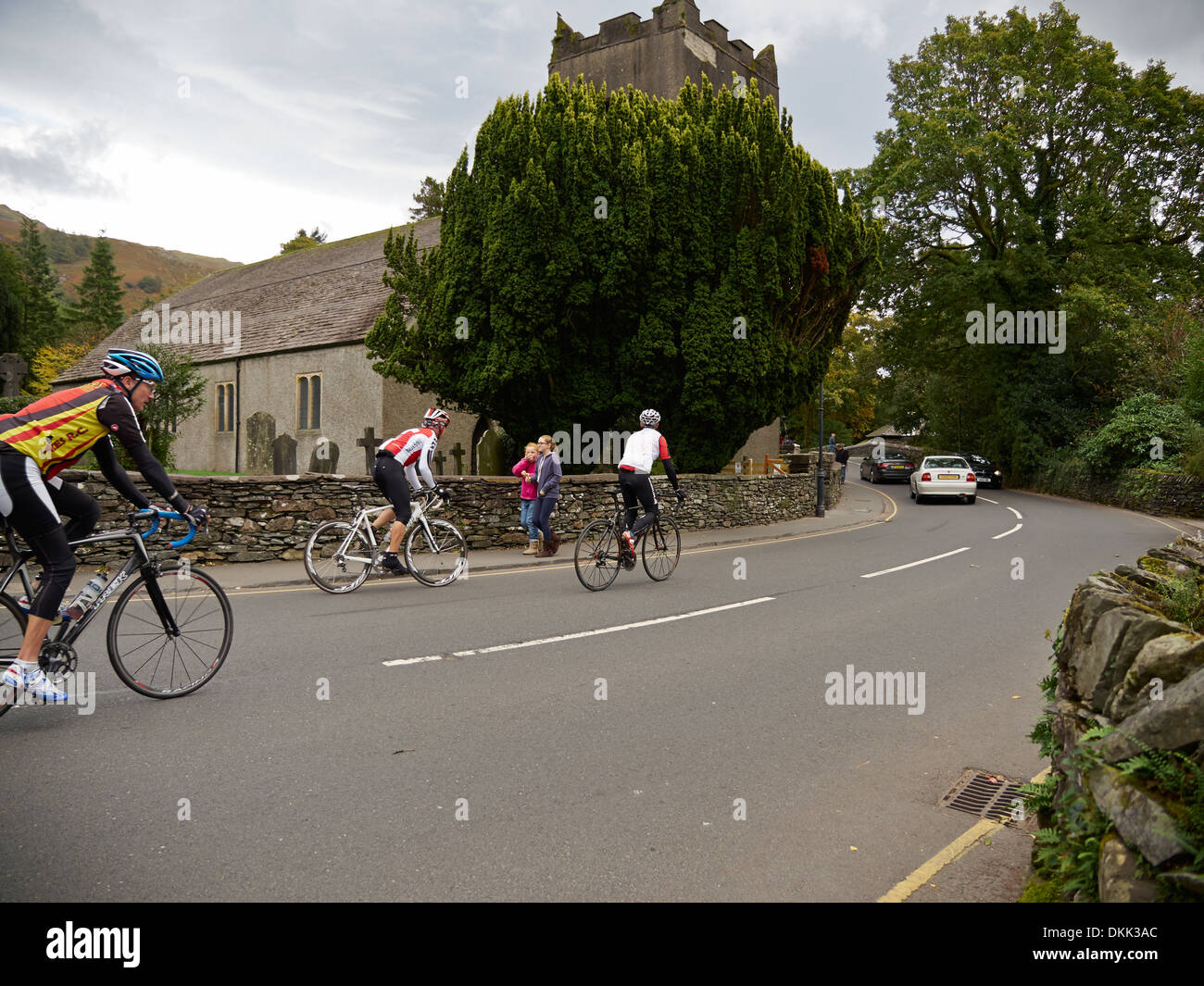 I ciclisti su strada a Grasmere, Cumbria. Uno è a cavallo in mezzo alla strada. Foto Stock