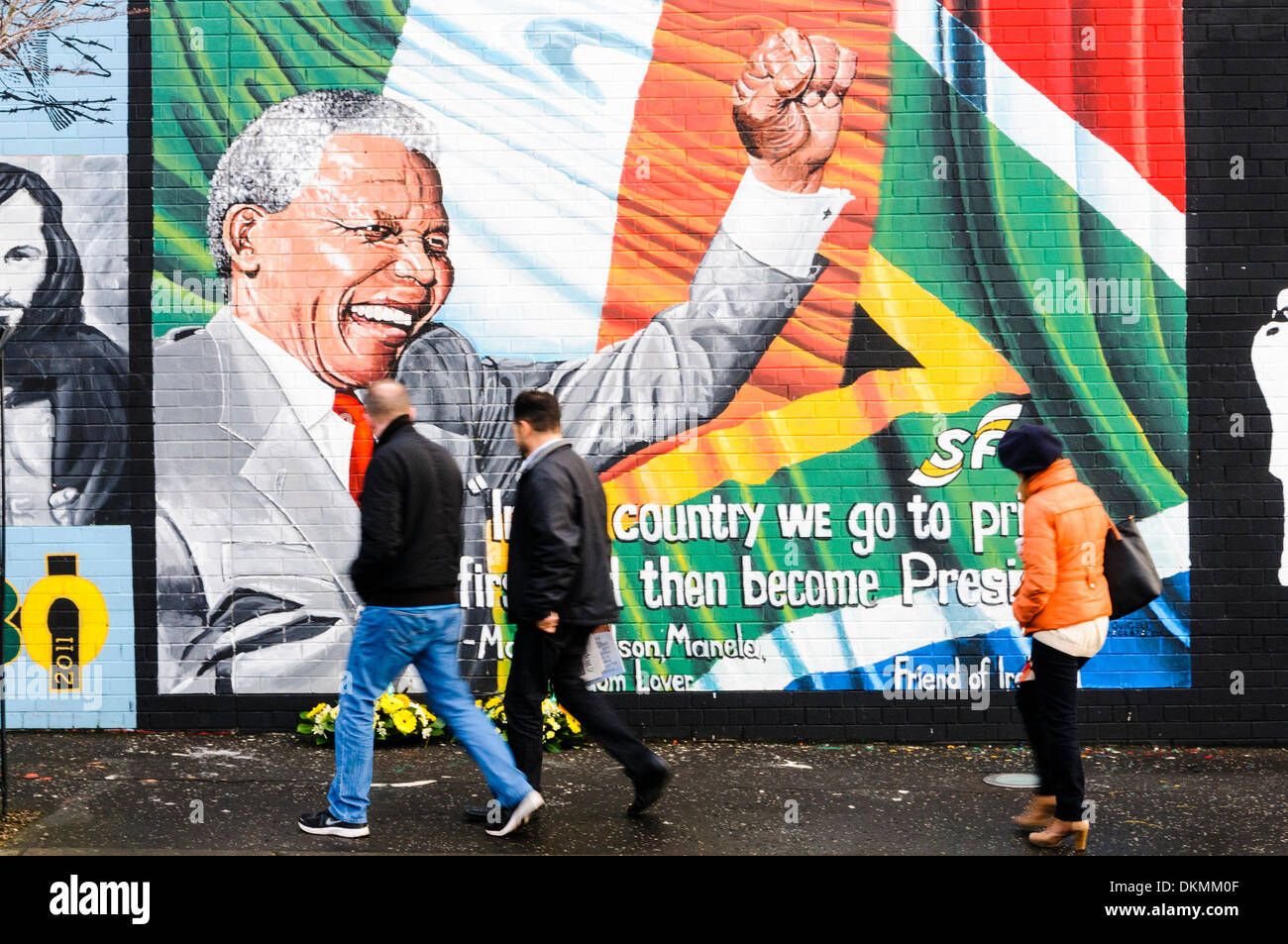 Belfast, Irlanda del Nord. 7 Dic 2013 - Le persone passano da omaggi floreali a sinistra a Mandela Murale in seguito alla morte di Nelson Mandela il 5 dicembre. Credito: Stephen Barnes/Alamy Live News Foto Stock
