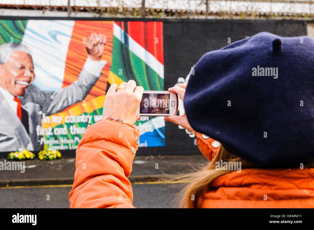 Belfast, Irlanda del Nord. 7 Dic 2013 - Una donna scatta una fotografia del Nelson Mandela murale utilizzando un iPhone. Credito: Stephen Barnes/Alamy Live News Foto Stock