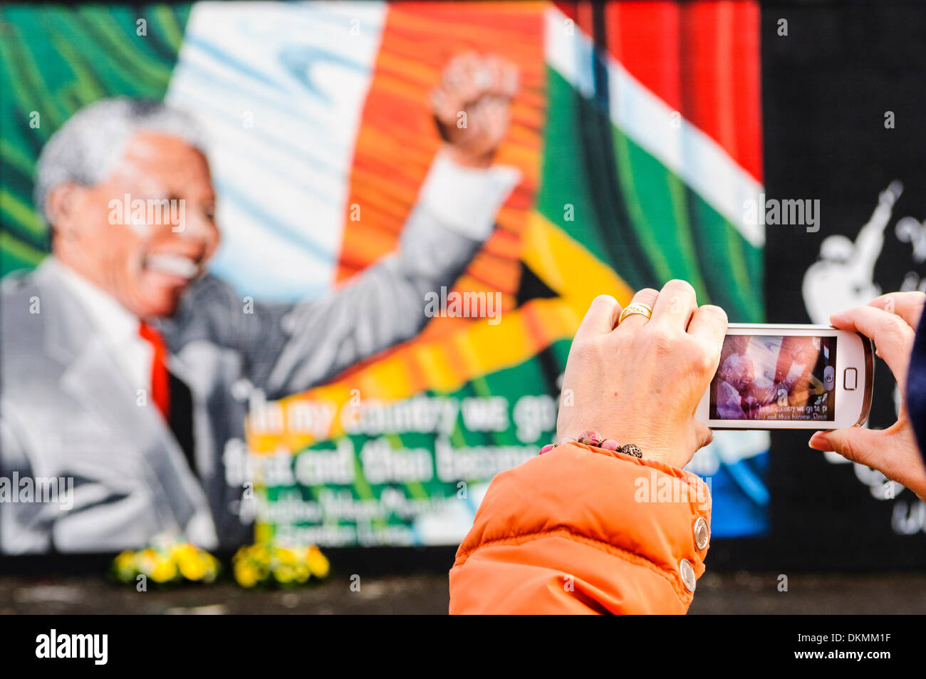 Belfast, Irlanda del Nord. 7 Dic 2013 - Una donna scatta una fotografia del Nelson Mandela murale utilizzando un iPhone. Credito: Stephen Barnes/Alamy Live News Foto Stock