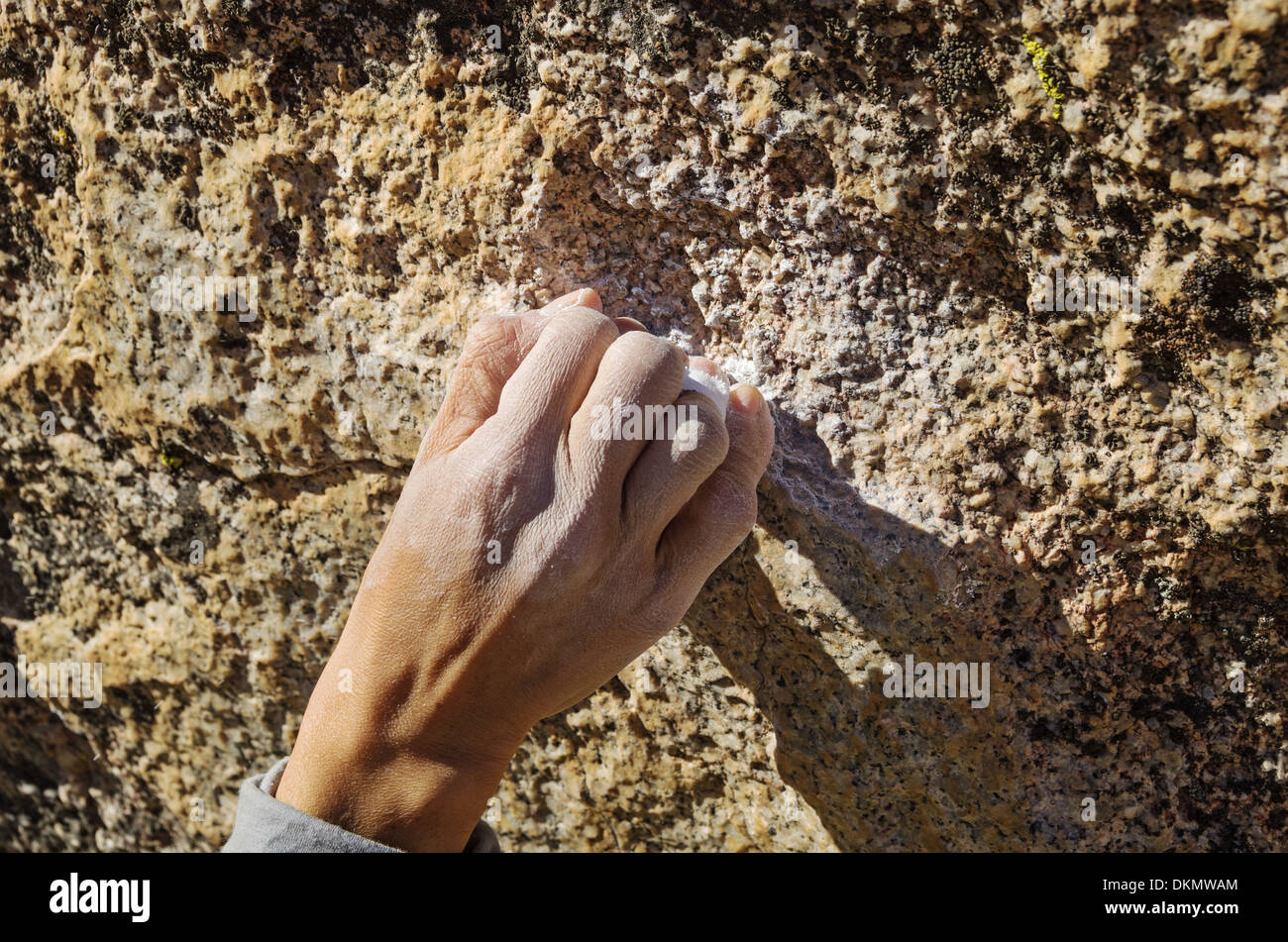 Una donna scalatore mano afferrando una piccola roccia di attesa con una presa a crimpare Foto Stock