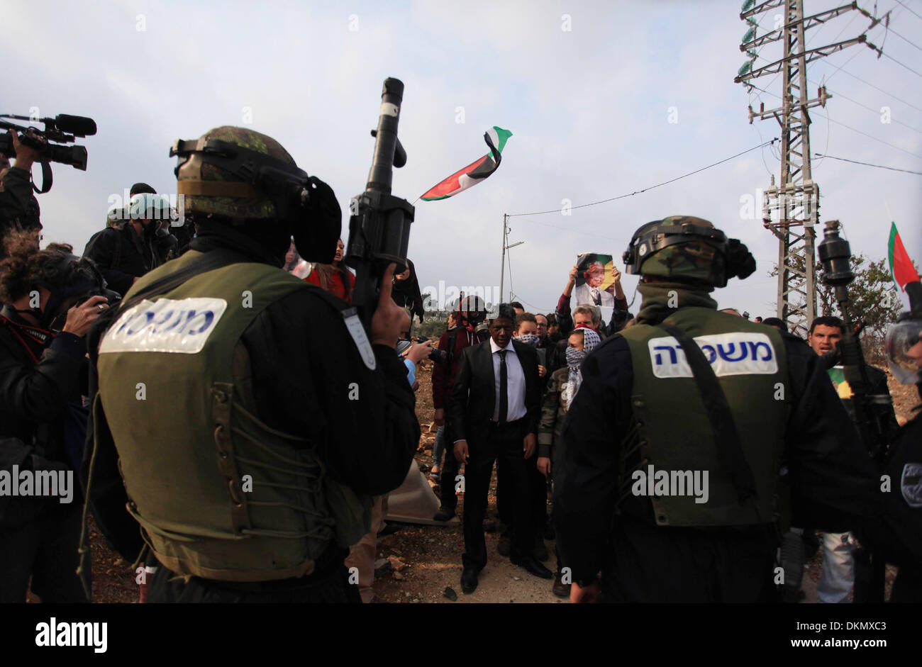 Ramallah, West Bank, Territorio palestinese . Il 7 dicembre, 2013. Soldati israeliani spostare un uomo palestinese, come egli detiene un poster del compianto leader sudafricano Nelson Mandela, durante una manifestazione di protesta contro la costruzione di un vicino insediamento ebraico israeliano Cisgiordania occupata il 7 dicembre 2013, nel villaggio palestinese di Nabi Saleh, a ovest di Ramallah. I leader palestinesi ha attirato l' eredità di Nelson Mandela, un alto profilo sostenitore della loro causa, paragonando la sua lotta contro l apartheid alla loro lotta per la fine occupazione Israeliana Credito: Issam Rimawi APA/images/ZUMAPRESS.com/Alamy Live Foto Stock