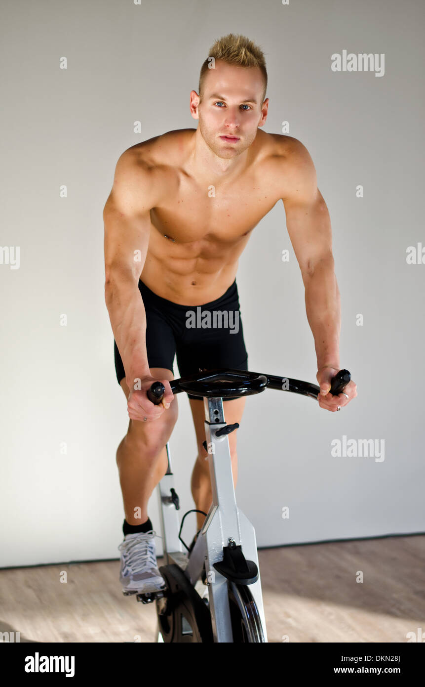 Attraente giovane di esercizio in palestra, filatura sulla cyclette Foto Stock