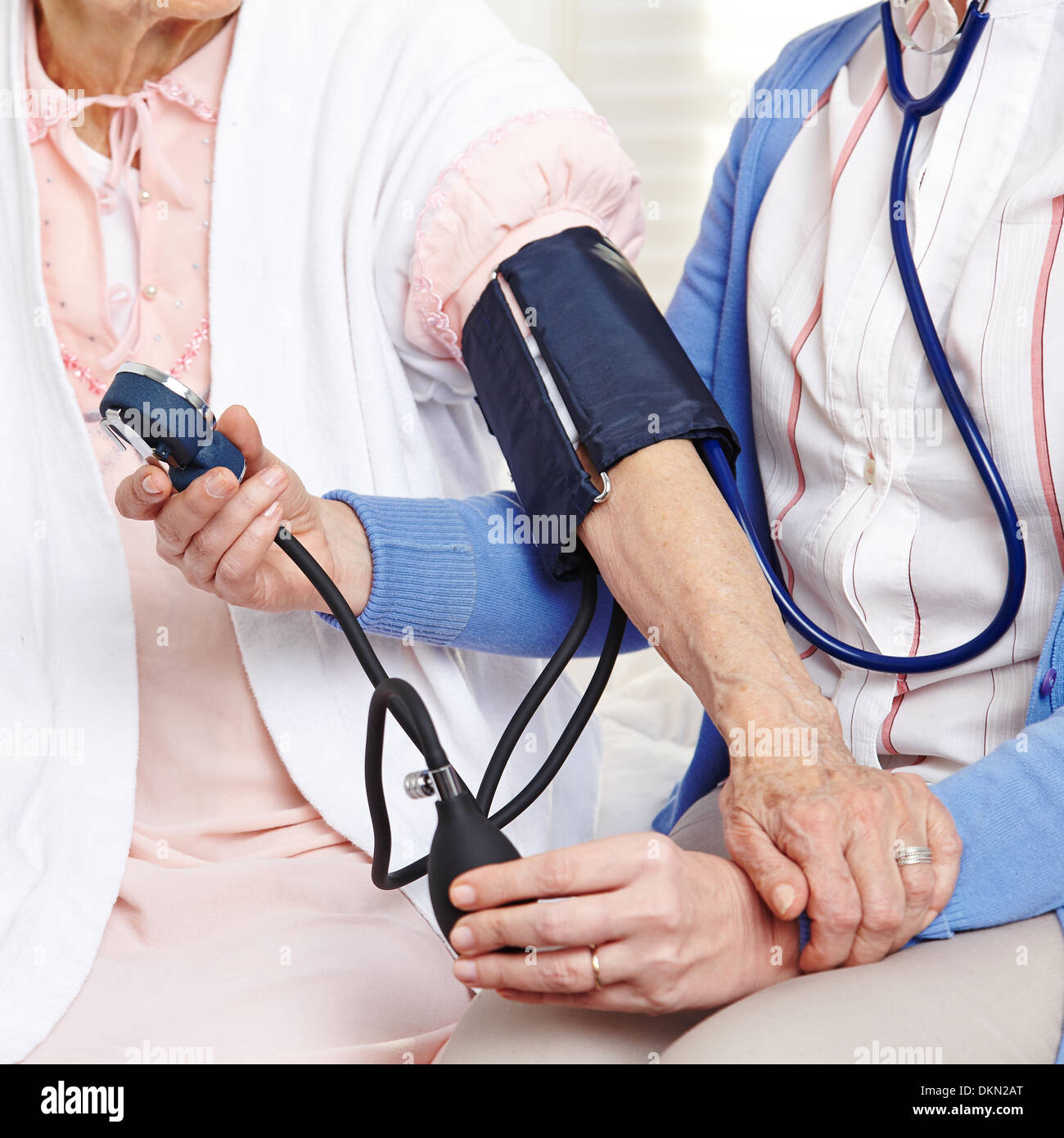 La misurazione della pressione sanguigna in casa di cura sulla donna senior Foto Stock