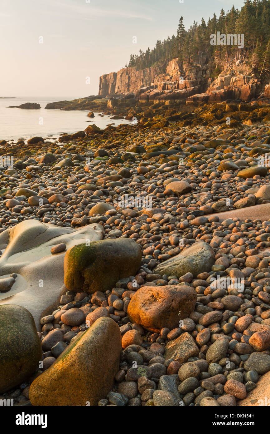 Pietre arrotondate sulla spiaggia di Boulder guardando verso la lontra scogliere a sunrise nel Parco Nazionale di Acadia, Maine Foto Stock