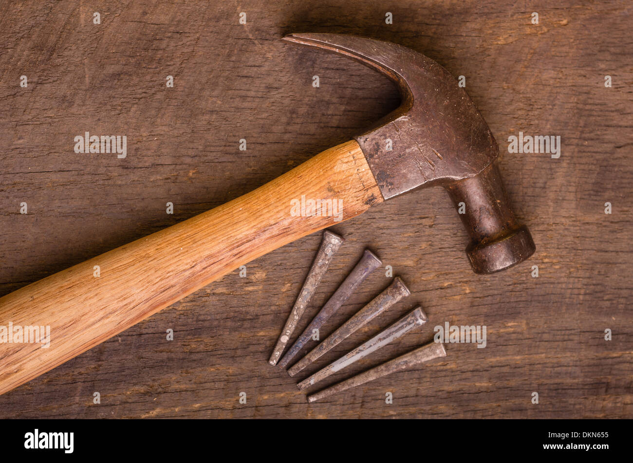 Un martello e chiodi su una vecchia tavola di legno Foto Stock