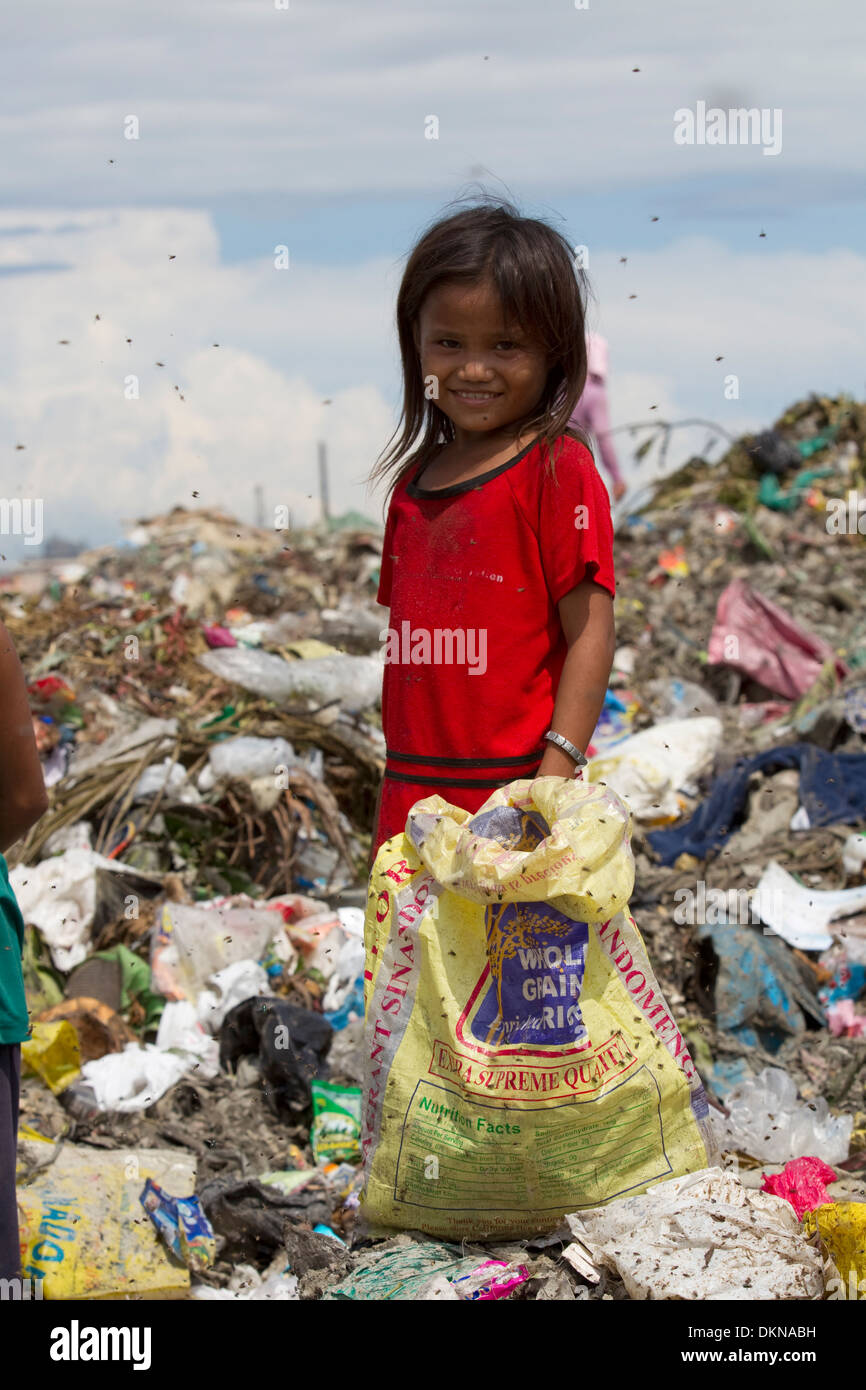 Un bambino circondato da mosche,per il lavaggio di oggetti di valore entro il Inayawan discarica dei rifiuti sito,Cebu City, Filippine Foto Stock