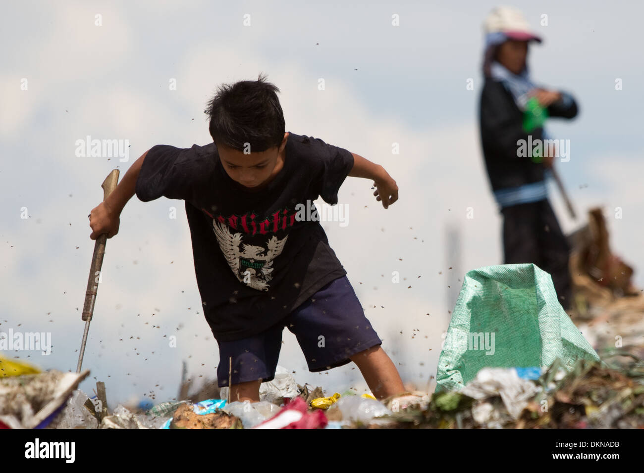 Un bambino circondato da mosche,per il lavaggio di oggetti di valore entro il Inayawan discarica dei rifiuti sito,Cebu City, Filippine Foto Stock