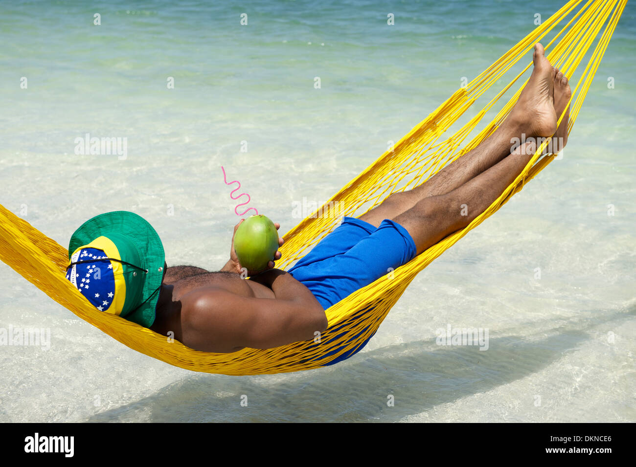 L uomo si rilassa in amaca sulla spiaggia brasiliana di bere acqua di cocco  Foto stock - Alamy