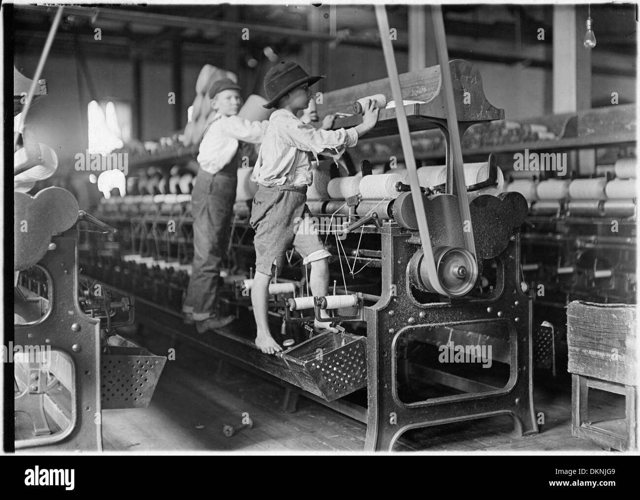 I bambini lavorano al Bibb Mill No. 1 a Macon, Georgia, all'inizio del XX secolo. Alcuni sono così piccoli che devono salire sulle macchine, riflettendo lo sfruttamento del lavoro minorile nell'industria tessile. Foto Stock
