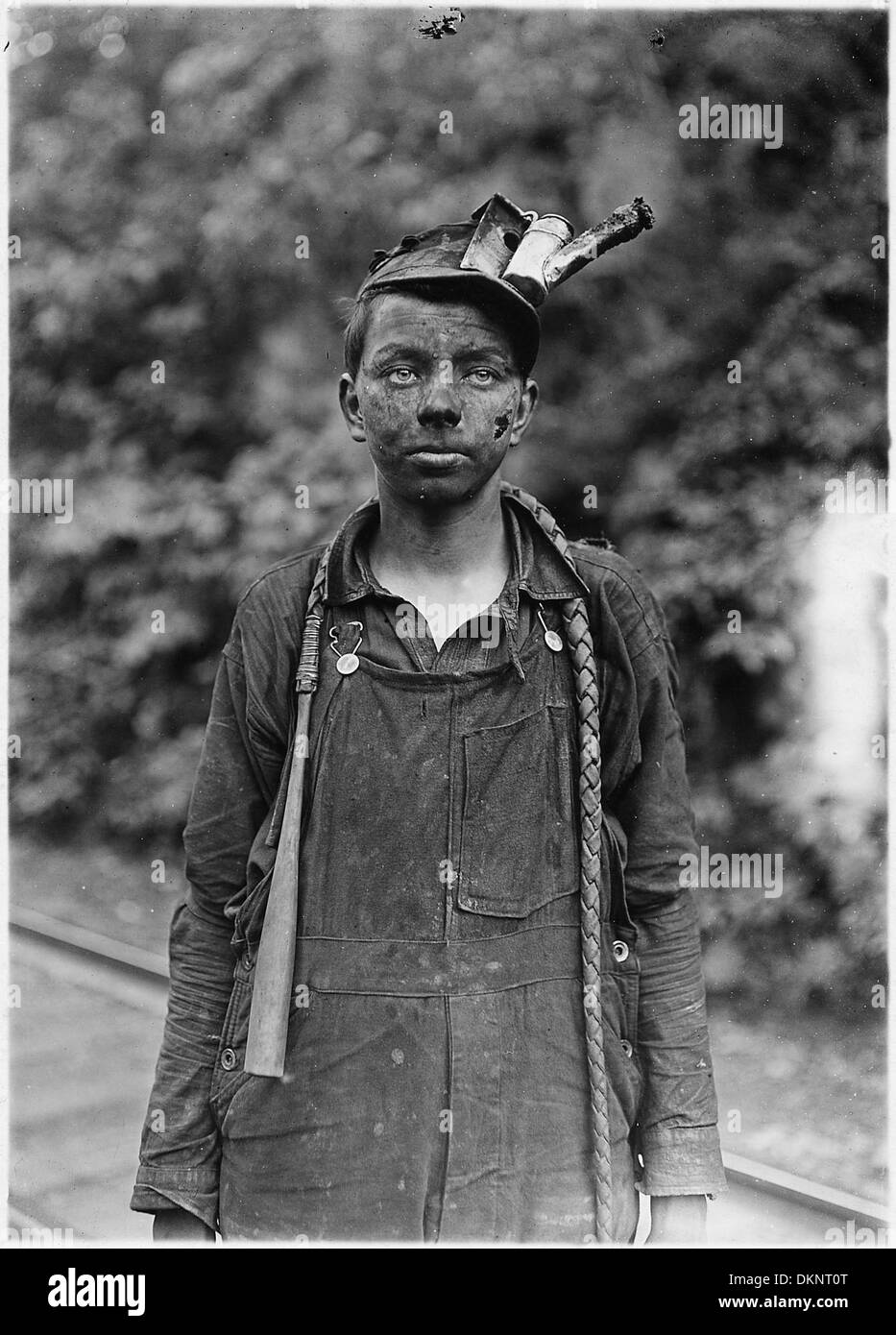Questa fotografia cattura un giovane conducente che utilizza macchinari in una miniera, mostrando le sfide e le responsabilità affrontate nelle attività minerarie sotterranee. Foto Stock