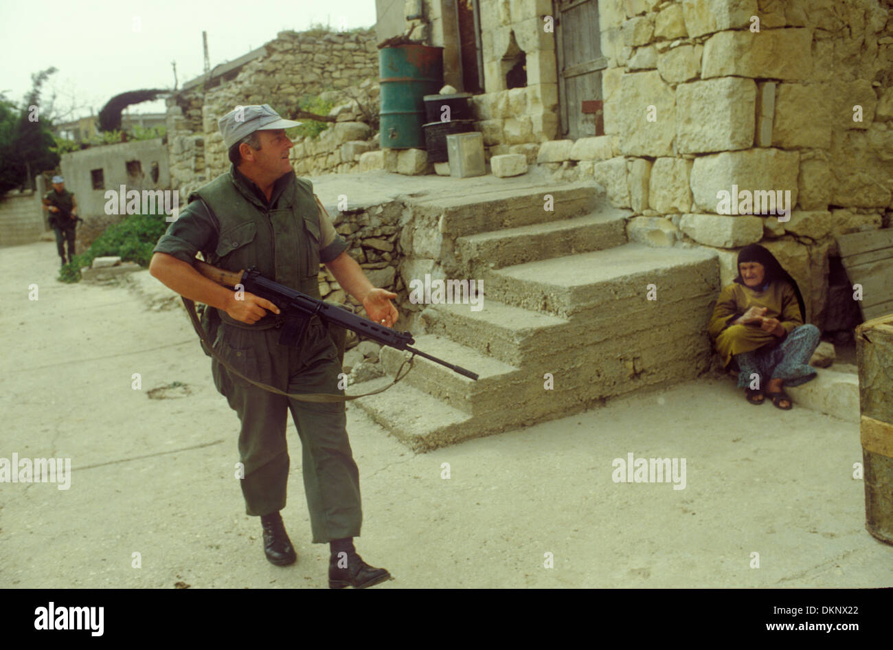 Le truppe irlandesi delle Nazioni Unite nel sud del Libano lavorano attraverso una signora locale di un villaggio di montagna che si tiene lontano mentre i soldati passano davanti. 1980 1980 anni HOMER SYKES Foto Stock