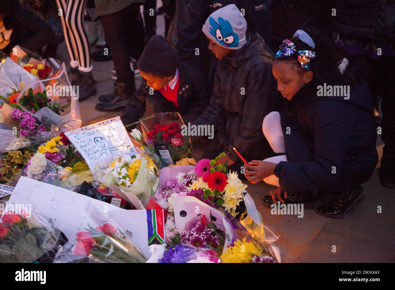 Londra, Regno Unito. L'8 dicembre, 2013. I bambini accendono le candele in omaggio a Nelson Mandela, a Piazza del Parlamento, London, Regno Unito Credito: galit seligmann/Alamy Live News Foto Stock