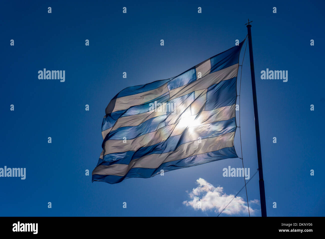 Grande bandiera greca sventola contro il sole blu cielo contro il sole, con nuvole bianche Foto Stock