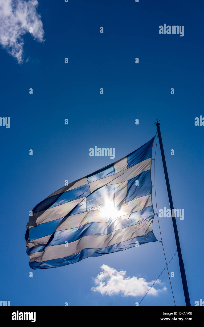Grande bandiera greca sventola contro il sole blu cielo contro il sole, con nuvole bianche Foto Stock
